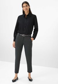 Schwarzes Button-up Hemd mit langen Ärmeln, kombiniert mit dunklen grauen tapered Pants. Ein Gürtel im Leopardenprint und schwarze Ballerinas vervollständigen das Outfit.