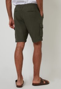 Grüne Cargo-Shorts mit einem elastischen Bund, zwei Seitentaschen und zwei Gesäßtaschen. Weicher Stoff mit glatter Textur, knielang.