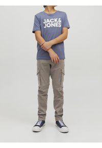Modré tričko s krátkým rukávem a bílým textem "JACK & JONES", spárované se světle šedými cargo kalhotami a námořnickými teniskami s bílou podrážkou.