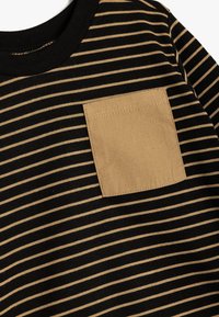 Czarny i beżowy t-shirt w paski z kieszonką w kształcie kwadratu z materiału w jednolitym odcieniu beżu, okrągłym dekoltem i miękką teksturą.