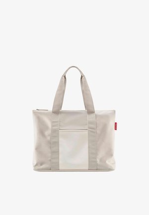 Beige rectangular tote bag with dual handles, front pocket, and a small red tag on the side, made of fabric material.