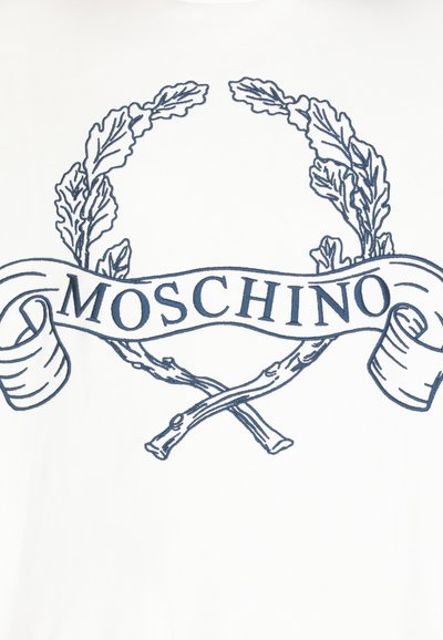 T-shirt bianco con un design grafico blu, che include una corona d'ulivo e un banner con il testo "MOSCHINO", circondato da rami stilizzati.