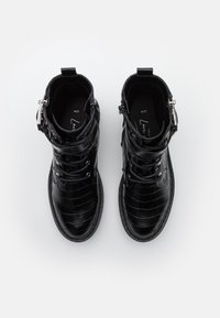 Černé kotníkové boty s krokodýlím vzorem, vybavené bočním zipem, předními šňůrkami a stříbrnými kovovými doplňky. Vnitřek je černý s logem.