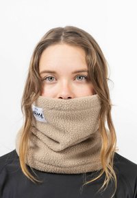 Gaiter en polaire beige avec une texture douce, portant une étiquette avec le nom de la marque. Porté autour du cou, couvrant une partie du bas du visage.