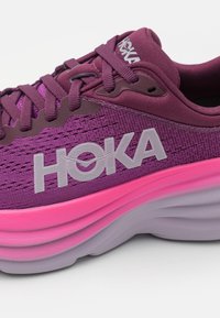 Scarpa da corsa HOKA viola con tomaia in rete testurizzata, suola spessa rosa e lavanda e logo bianco prominente sul lato.