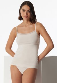 Beige camisole with thin straps and lace trim at the neckline, made from soft, stretchy fabric, paired with matching brief underwear.