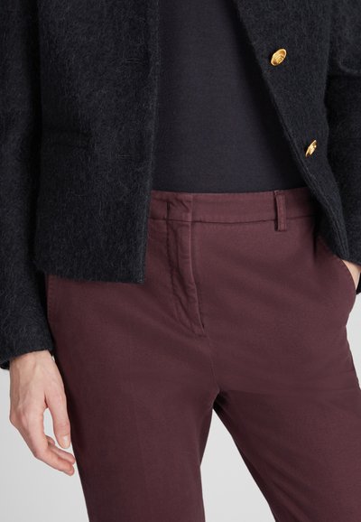 Czarny, puszysty żakiet z wełny z złotymi guzikami, zestawiony z burgundowymi spodniami z bawełny. Zbliżenie pokazujące fakturę materiału i dopasowanie.