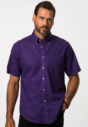 Camisa de manga corta abotonada en suave algodón púrpura. Presenta un bolsillo en el pecho y botones plateados a lo largo de la tapeta. Tejido suave y texturizado.