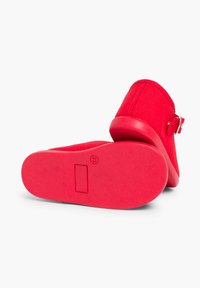 Scarpe rosse in tessuto con una tomaia texturizzata, dotate di punta rotonda, tacco basso e una fibbia argentata di lato. Suola in gomma piatta.