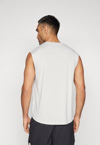 Ärmelloses graues Sporttanktop aus strukturiertem Material, mit Rundhalsausschnitt und lockerer Passform, sichtbaren Nähten und Rückendetails.