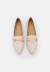 Beżowe baleriny z ostrym noskiem, wykonane z gładkiej skóry, z akcentem w postaci łańcuszka w kolorze złotym na wierzchu stopy oraz minimalnymi detalami przeszyć.