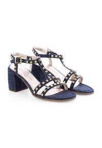 Denim-Absatzsandalen mit T-Riemen-Design, goldenen Nietenakzenten und Blockabsatz. Mit verstellbarem Schnallenverschluss und offenem Zehenbereich.