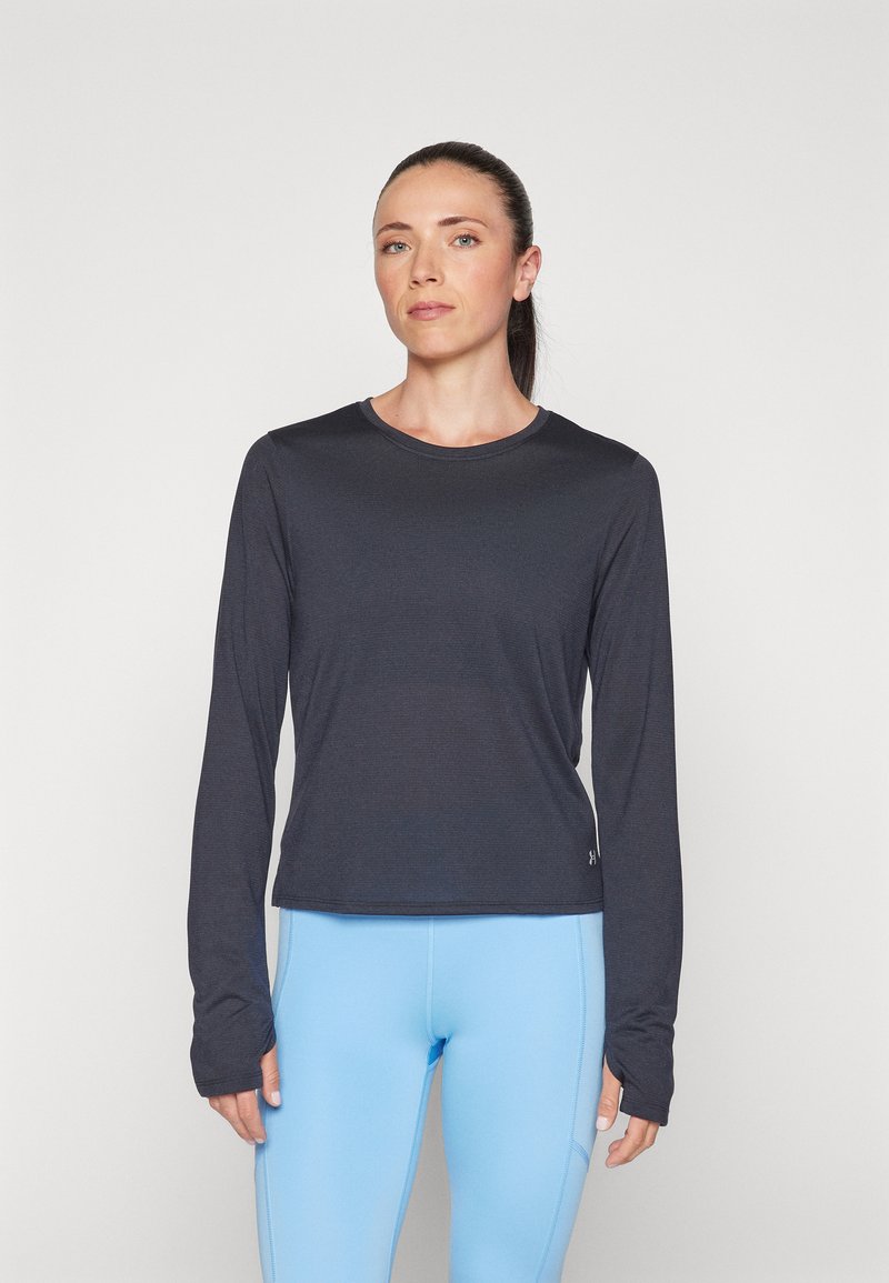 Camiseta deportiva de manga larga gris oscuro con cuello redondo, fabricada con un tejido ligero y presenta orificios para los pulgares en los puños, combinada con leggings azul claro.