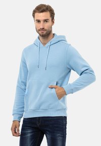 Helles blaues Pullover-Hoodie aus weichem Stoff, mit einer vorderen Taschenklappe, verstellbarem Kordelzug-Haube und gerippten Bündchen.
