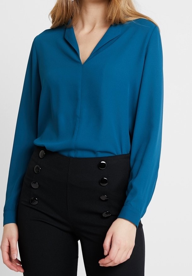 Bluzka z długim rękawem w kolorze morskim z kołnierzem w kształcie litery V, połączona z wysokimi czarnymi spodniami z dużymi czarnymi guzikami. Gładka tekstura.