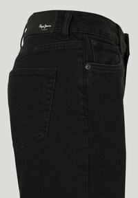 Svarta denimjeans med en åtsittande design, med en bakficka, vävd struktur och en logotyp patch på midjan.