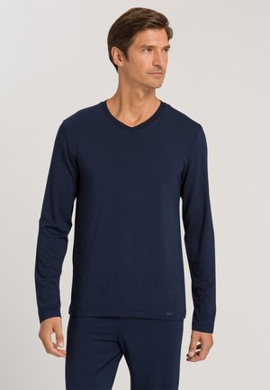 Marineblauwe langemouw V-hals shirt van een zachte, gladde stof. Heeft een casual pasvorm en subtiele branding aan de zoom. Minimalistisch ontwerp zonder patronen.