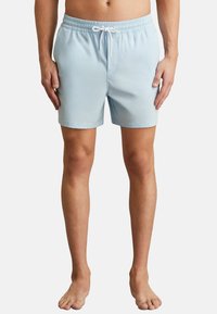 Pantaloni de baie de culoare albastru deschis, cu talie elastică și șnur. Construiți dintr-un material neted, cu buzunare laterale și o potrivire confortabilă.