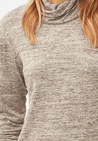 Jersey con cuello vuelto en un suave tejido de punto gris jaspeado. Cuenta con un bolsillo en el pecho y un ajuste relajado. Patrón texturizado en toda la prenda.