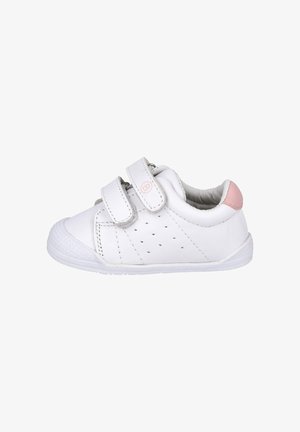 Zapatilla blanca para niño pequeño con dos tiras de Velcro, lado perforado, puntera texturizada y detalle rosa en el talón, vista desde el lado derecho.