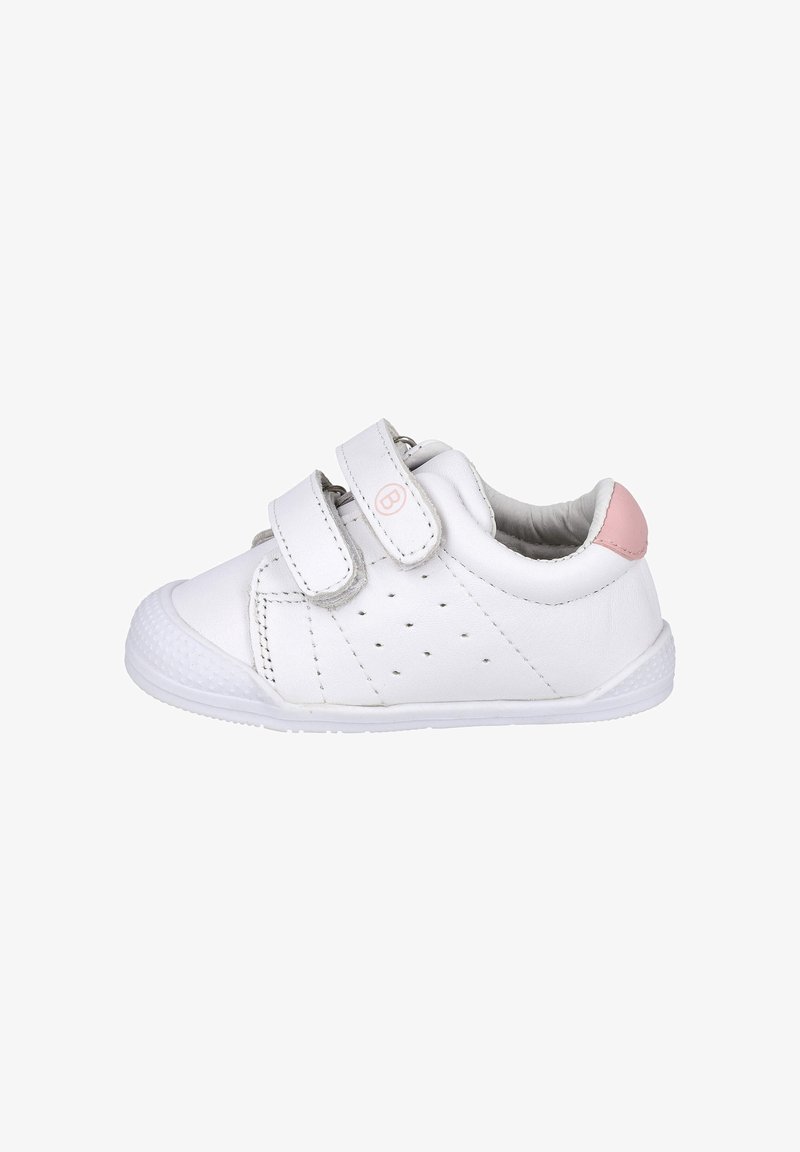 Zapatilla blanca para niño pequeño con dos tiras de Velcro, lado perforado, puntera texturizada y detalle rosa en el talón, vista desde el lado derecho.