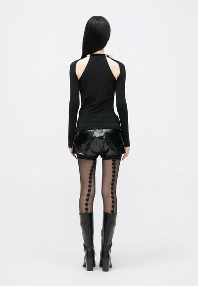 Fekete, hosszú ujjú felső, hátsó nyitott résszel, fényes fekete vinil sorttal párosítva. Fekete átlátszó harisnyák szív mintázattal, és térd fölé érő fekete csizmák.