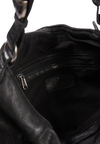 Svart läderhandväska med innerfack med dragkedja och mjuk tygfoder. Inkluderar rembeslag och en diskret varumärkesetikett.
