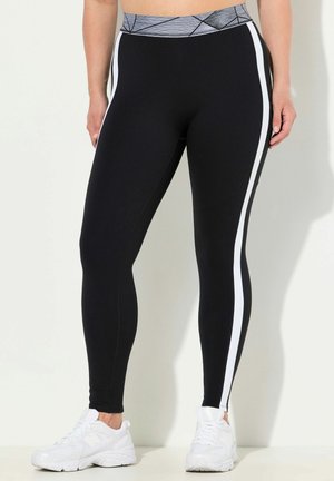 Leggings neri con strisce laterali bianche, una vita patterned grigia e una texture liscia e elastica. Indossati con scarpe da ginnastica bianche.