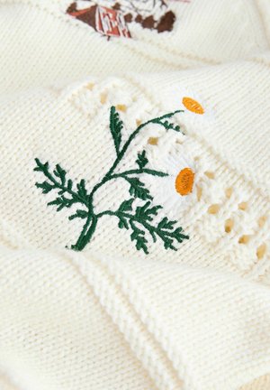 Cremefarbener Strickstoff mit kunstvoller grüner Stickerei von Blättern und orangen Blumen, mit dekorativen Spitzenakzenten entlang der Ränder.