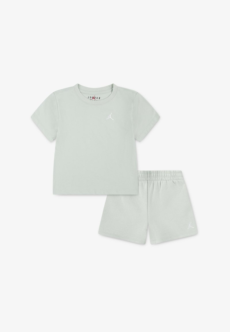 Šviesiai žalia medvilnė, trumpomis rankovėmis marškinėliai su baltu logotipu, derinami su atitinkamais šortais, turinčiais elastingą juosmenį ir logotipo akcentu.