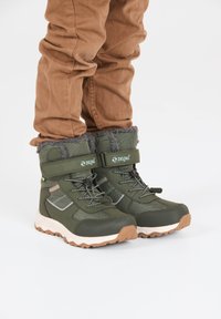 Groene winterlaarzen met een bovenwerk van textuurstof, een voering van bont, een verstelbare band en een robuule rubberen zool voor grip.