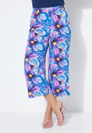 Blå bukser med vide ben med stort lilla og pink blomsterprint, båret med pink stropper high-heeled sandaler.