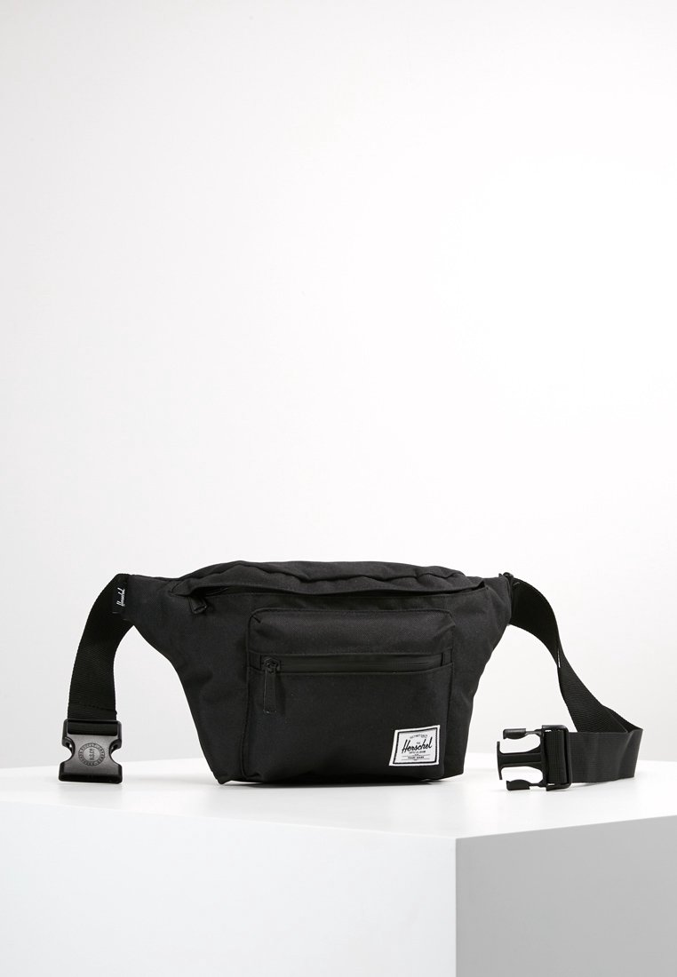 Černá nylonová ledvinka s nastavitelným popruhem, přední zipovou kapsou a logem. Disponuje hladkým povrchem a minimalistickým designem.