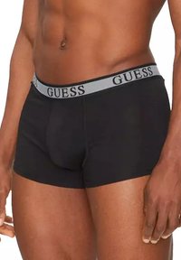 Boxers noirs avec une ceinture grise arborant le logo "GUESS". Fabriqués en tissu doux, ajustement confortable, avec une poche profilée pour le soutien.