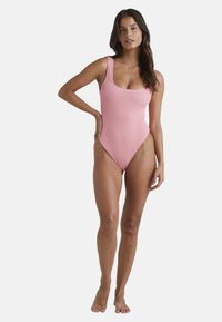 Costume da bagno intero rosa a costine con scollo tondo, spalline larghe, gambe a taglio alto e una texture liscia.