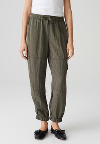 Lichte, olijfgroene joggers met een elastische tailleband, geribbelde manchetten en zichtbare naaddetails voor extra textuur.
