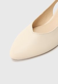 Beiger flacher Lederschuh mit spitz zulaufender Zehenpartie und V-förmigem Ausschnitt. Glatte Textur mit minimalen Nähten. Keine sichtbaren Beschläge oder Akzente.