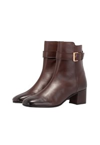 Brown leather ankle boots with a block heel, featuring a decorative strap and buckle detail, smooth texture, and pointed toe design.