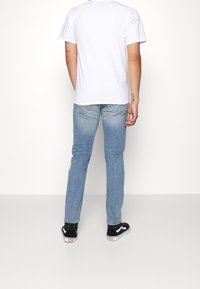 Vit bomull t-shirt matchad med ljusblå jeans. Har en standardpassform och en enkel design. Svarta sneakers fulländar looken.