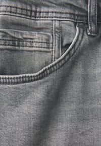 Vaqueros de denim en gris desgastado que cuentan con un bolsillo frontal, detalles de costura visibles y una textura suave con ligeras irregularidades.