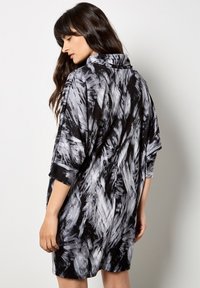 Luźna sukienka w czarno-szare wzory z kołnierzykiem, krótkimi rękawami i miękką teksturą, z widocznym wzorem pociągnięć pędzlem na materiale.