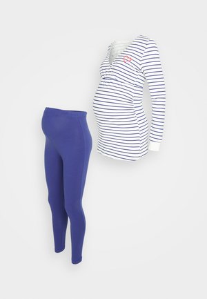 Top maternità a strisce bianche e navy, con scollatura a V e piccolo dettaglio a forma di cuore rosso, abbinato a leggings blu. Tessuto morbido e elastico.