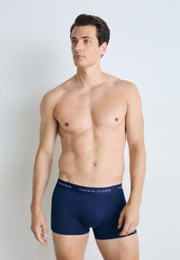 Kék pamut bokszalsó, márkázott derékpánttal, amelyen a "TOMMY HILFIGER" felirat található. Testhez simuló fazon, combközép hosszúságú, sima tapintású.