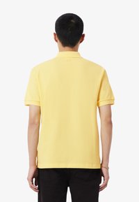 Polo gialla realizzata in tessuto di cotone con colletto a coste e maniche corte. Presenta un logo ricamato sulla nuca.
