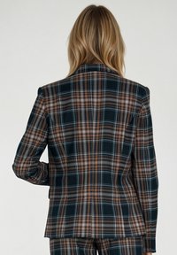Marynarka w kratę z ciemnozielonymi, pomarańczowymi i białymi liniami. Dopasowany fason z nowoczesnym krojem i wyraźnymi ramionami. Gładka tekstura materiału.
