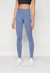 Vysoké športové legíny s elastickým pásom vyrobené z jemnej modrej látky, priliehavého strihu, hladkej konzistencie, bez viditeľných vzorov alebo ozdôb.