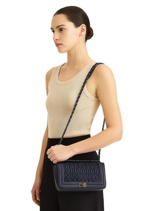 Borsa a tracolla in pelle trapuntata blu navy con chiusura dorata e tracolla in catena, forma rettangolare e superficie liscia.