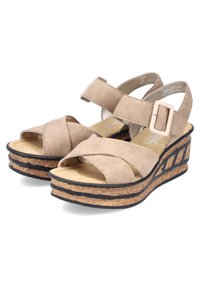 Sandali beige in suede con tacco a cuneo, dotati di fasce incrociate e una fibbia regolabile. Suola in sughero con dettagli neri e piattaforma testurizzata.