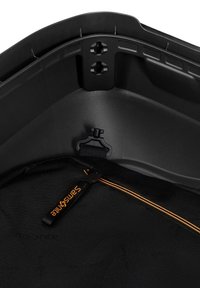 Black luggage interior with textured lining. Features an orange zipper with a branded pull tag and a plastic clip for securing items.