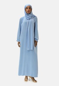 Lichtblauwe abaya met lange mouwen en bijpassende hijab, gemaakt van zachte stof met een vloeiend ontwerp. Eenvoudige en elegante details overal.